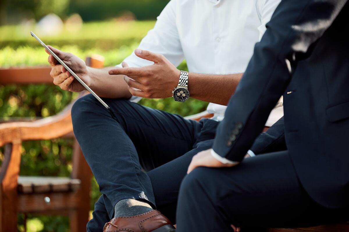 Two people sitting and pointing at a tablet